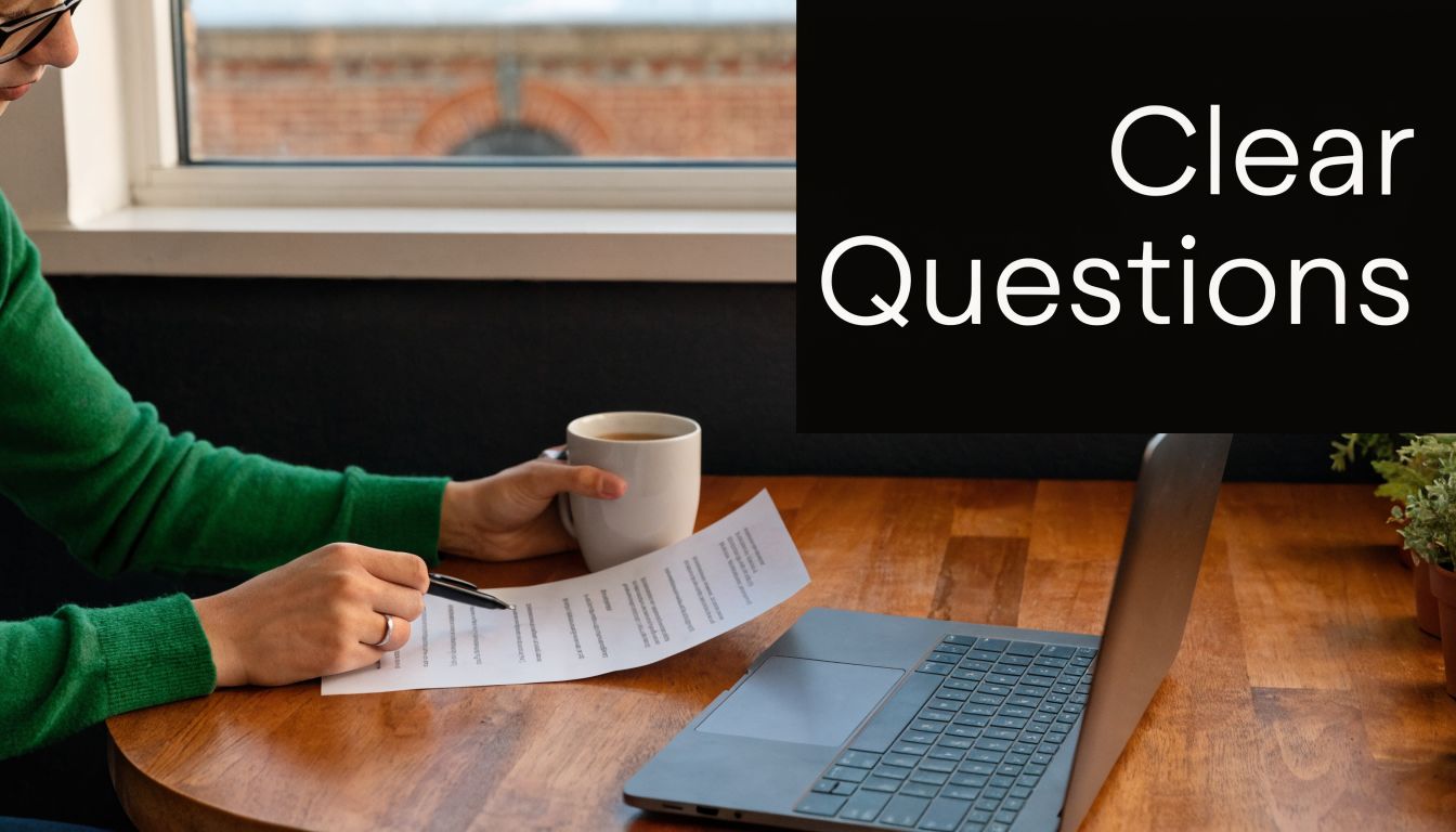 A person reviewing survey document while holding a coffee cup next to an open laptop on desk.